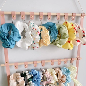 Detail of pink PU leather hair accessory organizer with wood rods and metal hooks