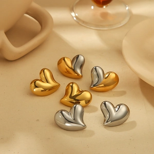 Polished chunky heart stud earrings in gold and silver mix finish on elegant tabletop