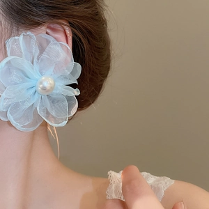 Detail of light blue chiffon flower earring with a central pearl on a model