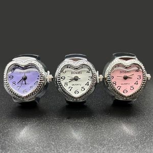 Three heart-shaped quartz ring watches in purple, white, and pink with silver metal cases