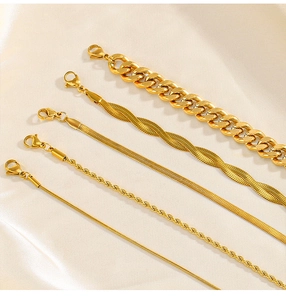 Detail view of five assorted gold snake and cuban link bracelets on silk fabric