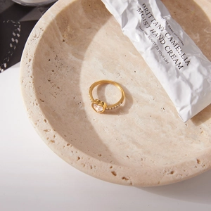 Dettaglio macro dell'anello a cuore in acciaio oro 18K con zirconi su vassoio in pietra