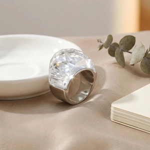 Fashionable oversized clear crystal ring with wide silver band on a minimalist background