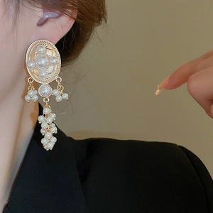 Detail of vintage gold tassel earrings with oval pearls on model's ear