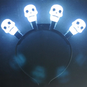 Detail shot of four glowing white LED skulls on a black Halloween party headband