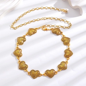 Close-up of golden vintage heart metal chain belt with intricate embossed floral patterns