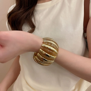 Close-up of a wide acrylic resin and gold-tone metal bracelet worn on a female wrist