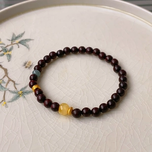 Detail of sandalwood bead bracelet with amber and turquoise charms on a vintage porcelain plate
