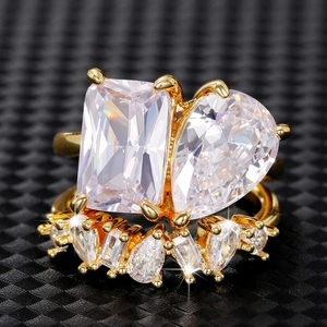 Detail of a Toi et Moi gold ring featuring emerald and pear cut crystals in a claw setting