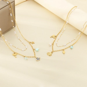 Detail of double-layer gold necklace featuring sea star, shell, and turquoise pendants