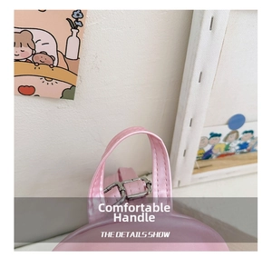 Close-up of pink leather handbag featuring a reinforced handle and silver metal buckle