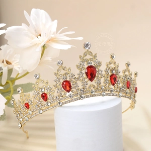 Detailed view of luxury gold crown with red teardrop gemstones on a display stand