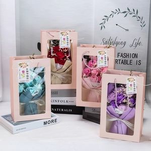Detail view of assorted soap flower bouquets in gift bags with elegant ribbons and tags