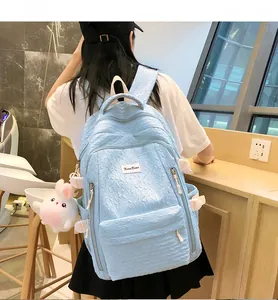 Vue détaillée du sac à dos bleu clair texturé avec charme lapin et rubans décoratifs