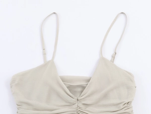 Détail d'un caraco en satin abricot avec décolleté plissé et fines bretelles