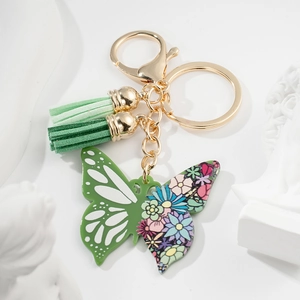 Green butterfly keychain with floral print, green tassels, and gold hardware on white
