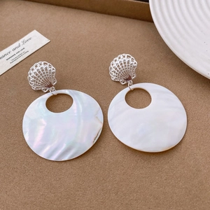 Macro detail of silver shell stud with round mother of pearl pendant earring