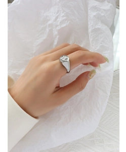 Macro shot of silver cupid angel embossed ring in minimalist aesthetic style on hand