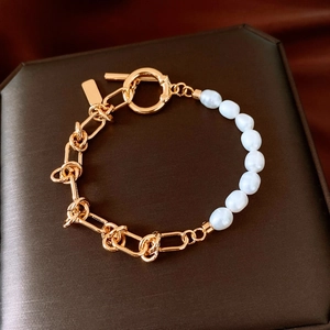 Detail of 18k gold plated pearl bracelet with OT clasp on brown leather background