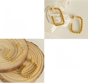 Detailed macro view of 18K gold plated twisted hoop earrings on various display props