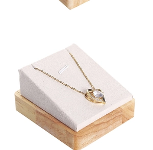 Detail of a gold heart necklace with a round gemstone on a wooden display stand