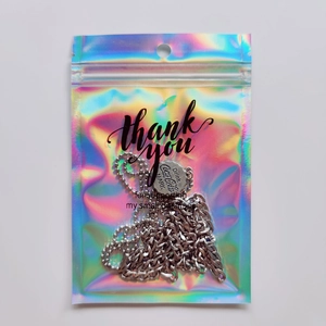Detail of bottle cap pendant inside a holographic laser ziplock bag with thank you text