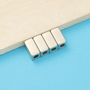 Macro detail of four silver rectangular spacer beads with brushed metal finish for DIY jewelry