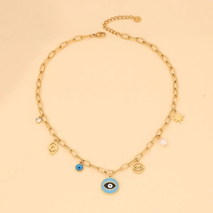 Close-up of gold star and evil eye necklace with pearls and zircon charms on beige background