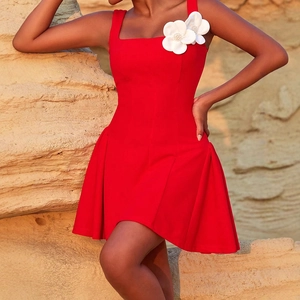 Détail de la robe courte rouge avec fleurs 3D blanches sur l'épaule et coupe trapèze