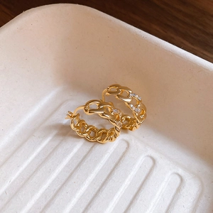 Close-up of gold-plated interlocking hoop earrings with small zircon stone settings