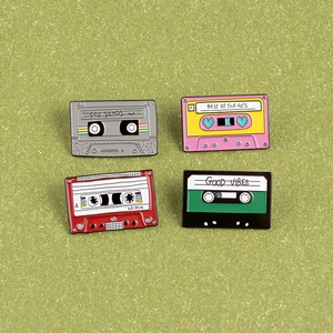 Close-up of four retro cassette tape enamel pins with Sad Songs and Good Vibes text