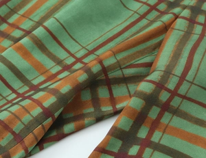 Detail of green and brown plaid woven fabric with soft drape and refined texture