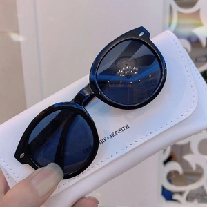 Detail of round black children's sunglasses on a white portable gallery carry case