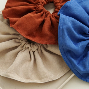 Detail of oversized fabric scrunchies in brown, beige, and blue with soft texture