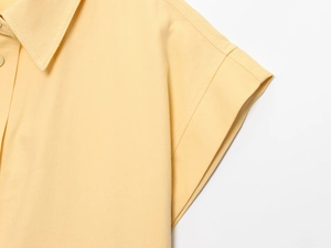 Gros plan sur l'ensemble en tissu sergé jaune montrant les détails de couture