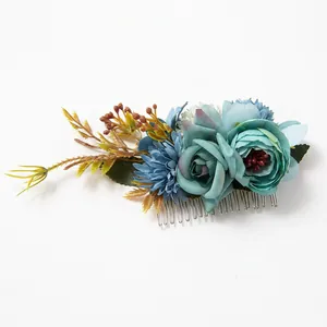 Close-up of Morandi blue silk flowers and green leaves on a silver metal hair comb