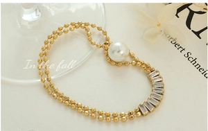 Detail of gold-plated layered bead bracelet with a large pearl and zircon crystals