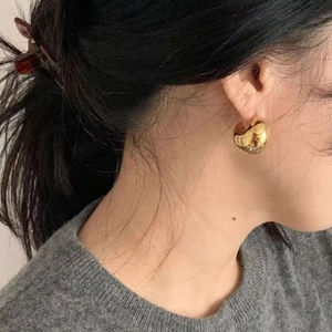 Chunky gold hollow hoop earrings in French vintage style worn by a model
