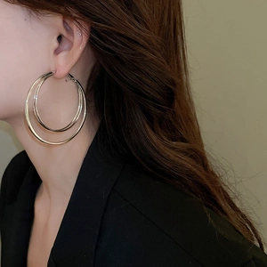 Vue de profil du mannequin portant des boucles d'oreilles créoles dorées à double couche