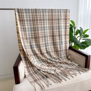 Detailed view of checkered cashmere-feel scarf with elegant fringes on armchair
