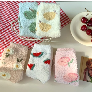 Détail de chaussettes en molleton corail à motifs de fruits dans un panier blanc