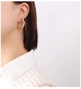Detailed side view of large 18K gold-plated C-shaped hoop earrings on a female model