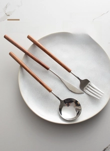 Detailed close-up of 304 stainless steel cutlery set with pearwood handles on a plate