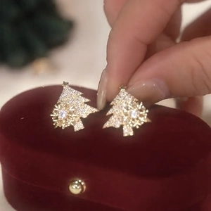 Close-up of golden Christmas tree studs with micro-pave cubic zirconia on red velvet box