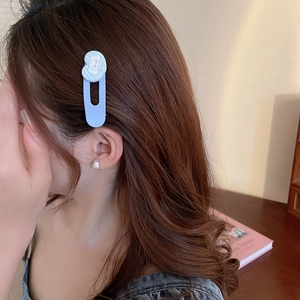 Vue détaillée d'une pince à cheveux nuage bleu clair sur de longs cheveux ondulés