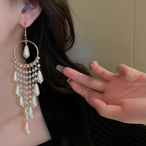 Elegant gold drop earrings with zircon circles and long faux pearl tassels on a model