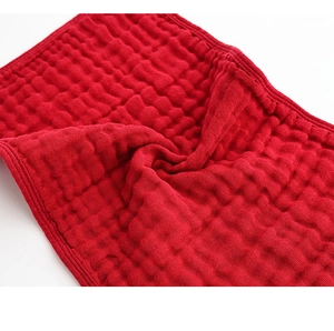 Detail of red six-layer cotton muslin burp cloth showing soft bubbled texture and edging