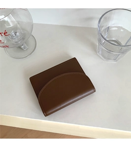 Detail of dark brown leather card holder featuring fine stitching and a semi-circular flap