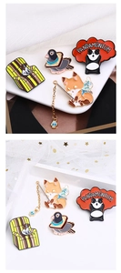 Detailed view of colorful enamel animal brooches featuring panda and fox on white silk