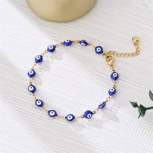 Close-up of blue enamel evil eye charm bracelet with golden chain and lobster clasp